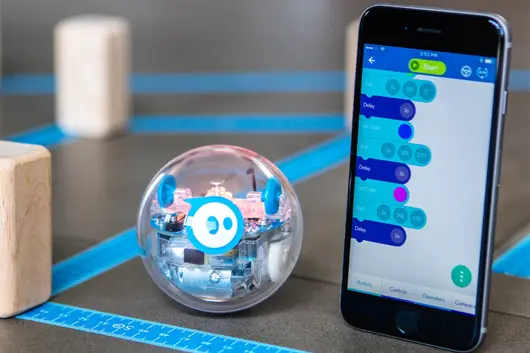 A Sphero Bolt coding robot next to an iPhone