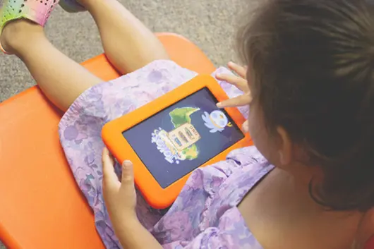 A young child playing with an orange Launchpad