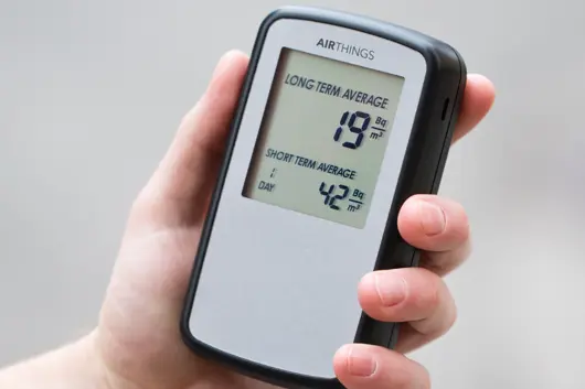 A hand holding a Radon Detector