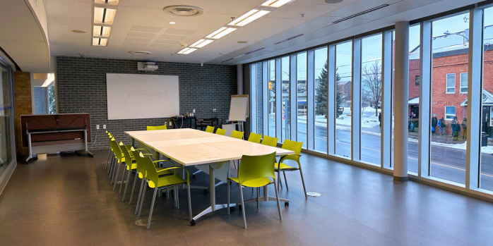 Multipurpose Room set up with tables in the middle and green chairs around it in a boardroom style setup