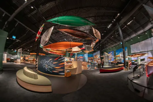 A view inside the Canadian Canoe Museum, many canoes suspended in the air on display