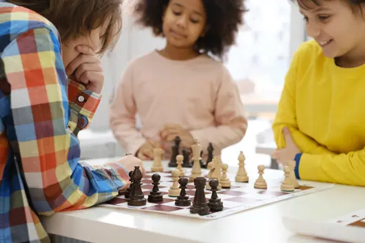 Three youth gathered around a chessboard